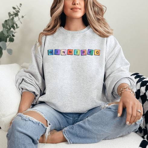 Introducing our newest addition to your wardrobe - the trendy graphic sweatshirt featuring colorful Winnipeg Scrabble Titles.